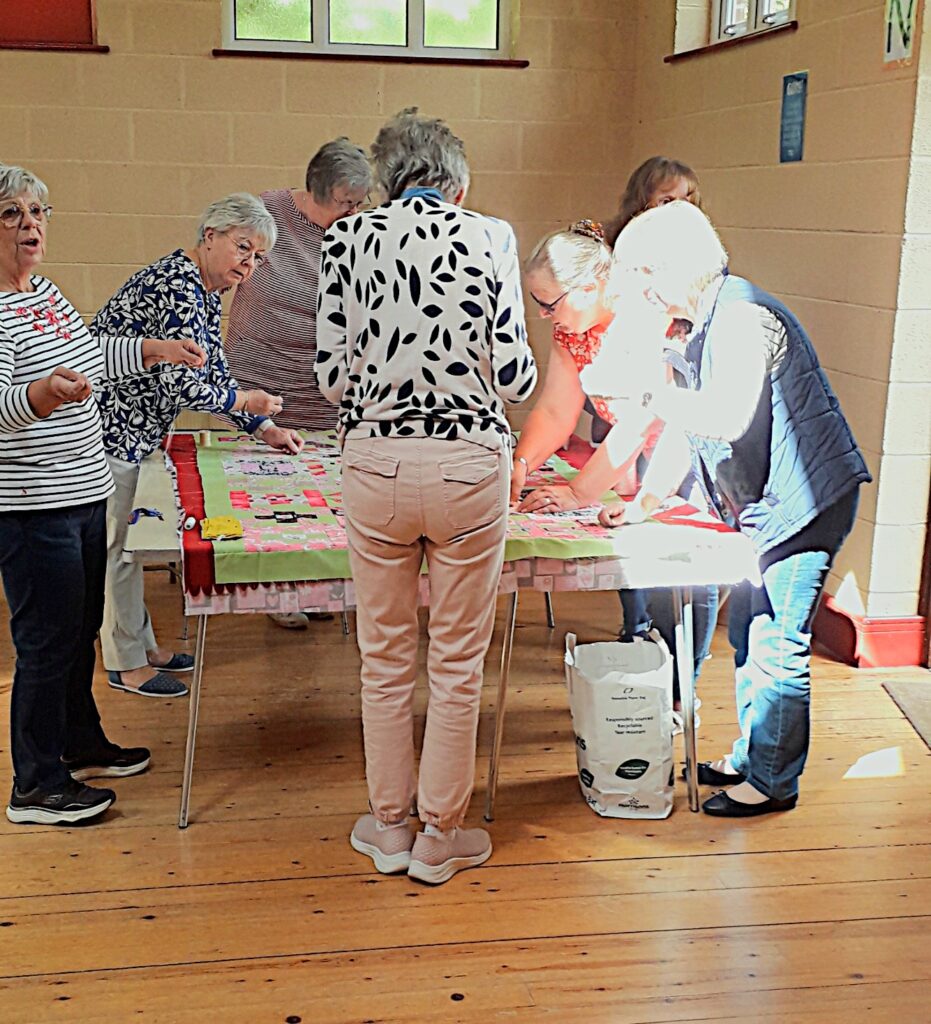 Members of the group tacking the quilt together